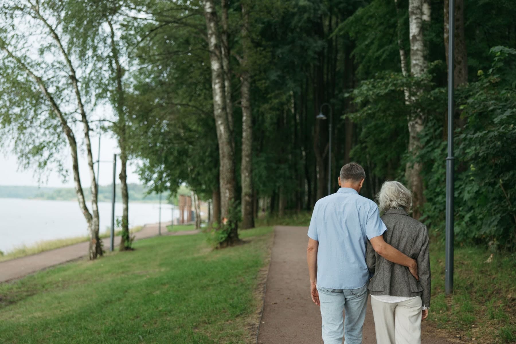 Two older adults walking on a wooded trail