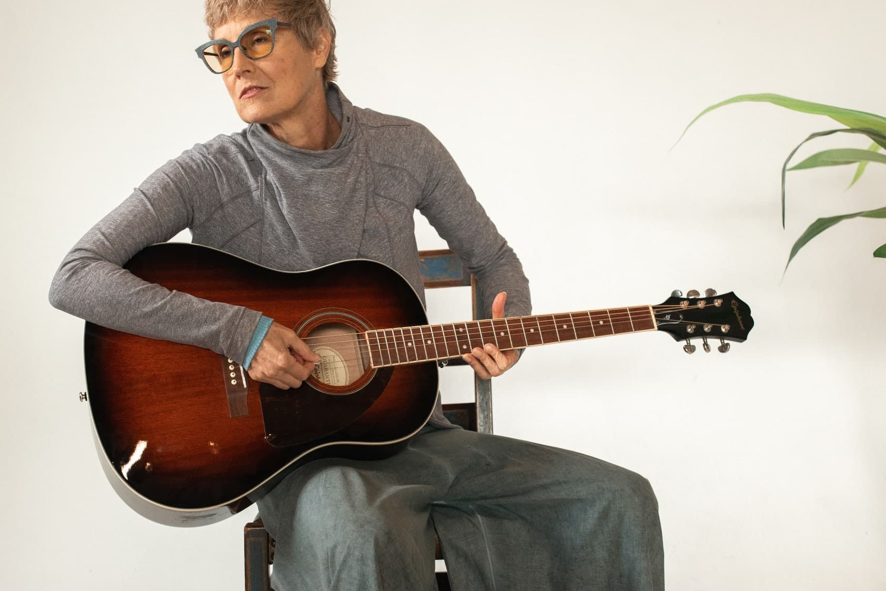 Woman in her 60s learning to play an acoustic guitar