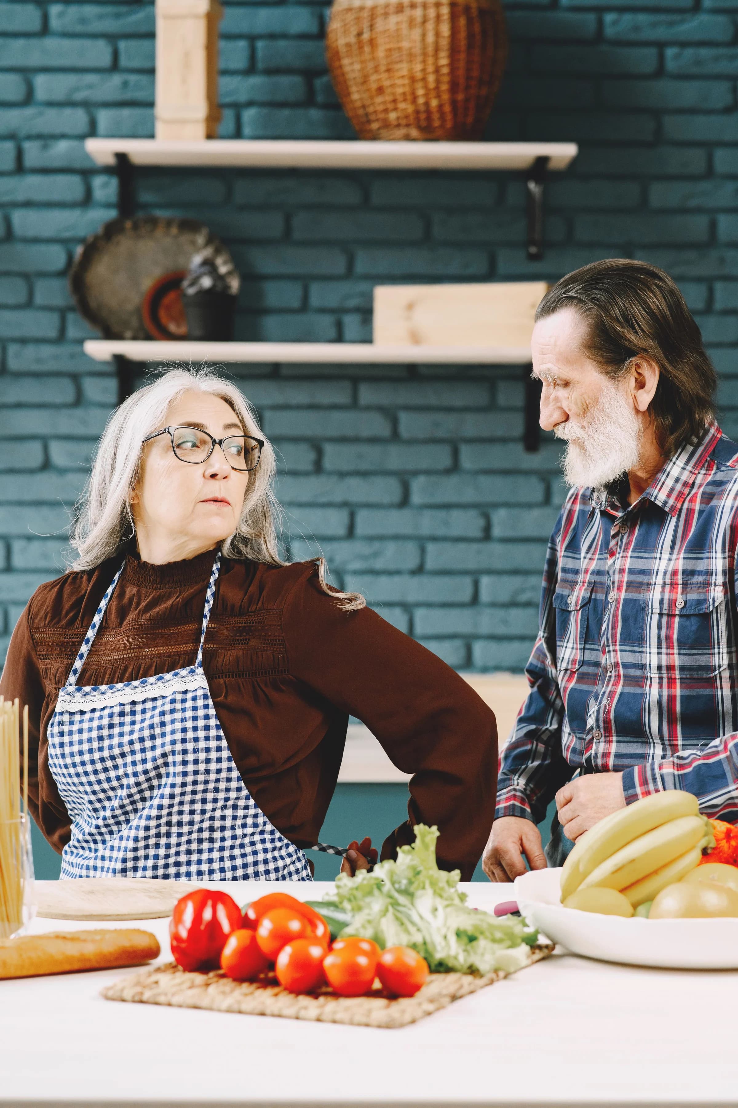 Older couple wearing aprons together in a kitchen.