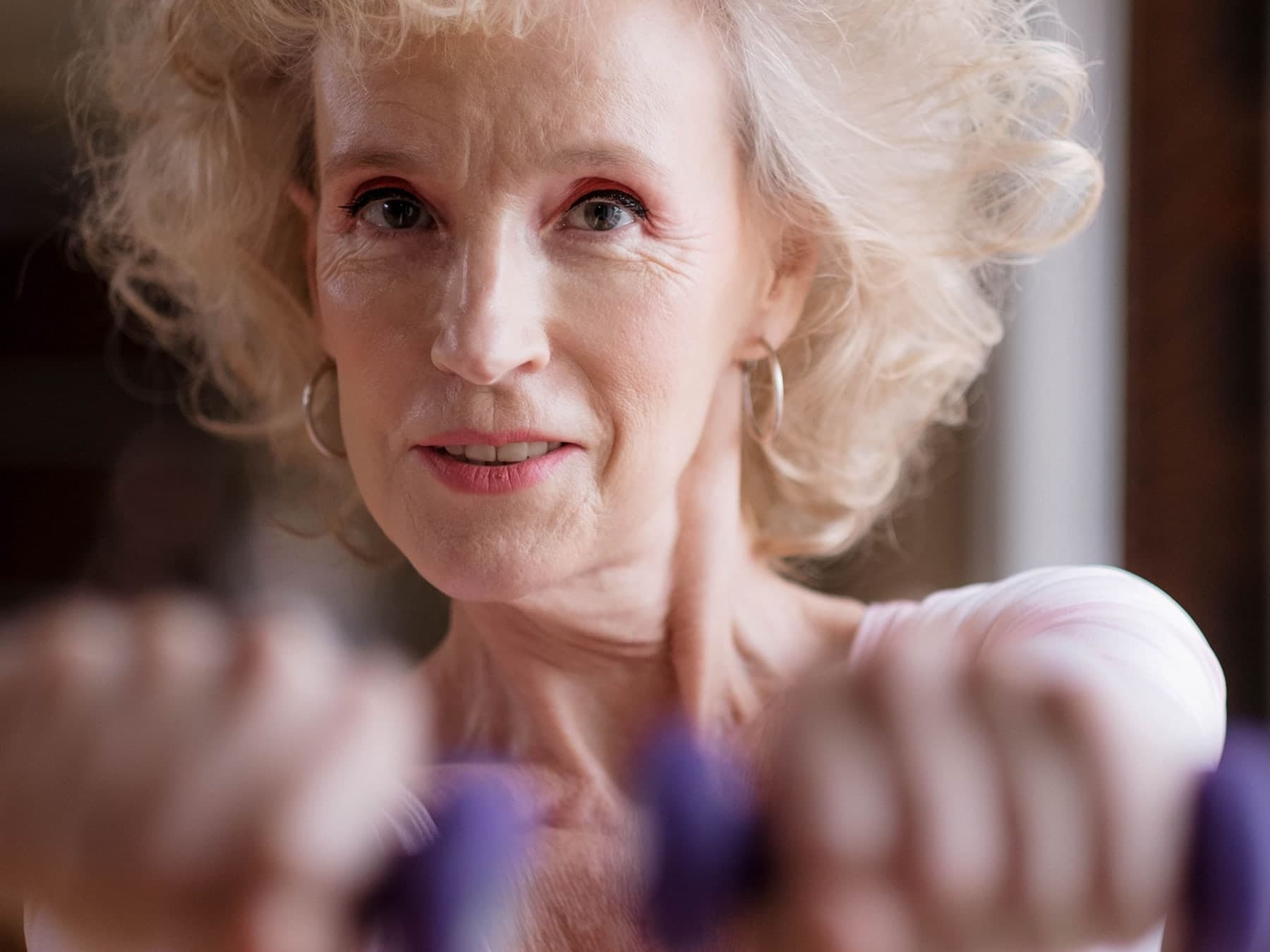 Older woman with white hair extending purple hand weights in front of her