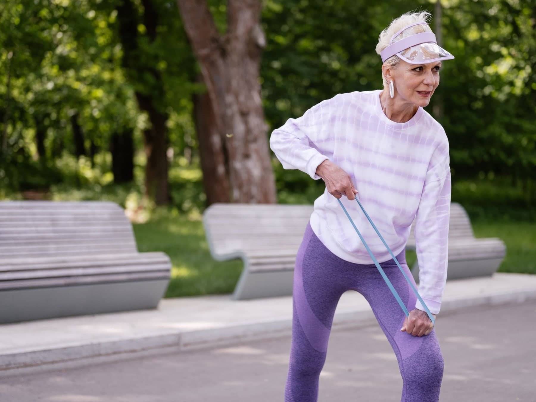 Older woman exercising with a resistance band outdoors in a park